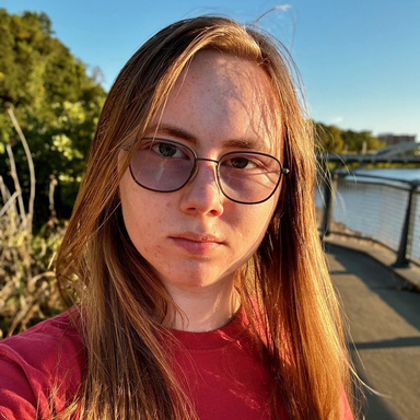 young person, shoulder length brownish hair, wearing glasses, red shirt