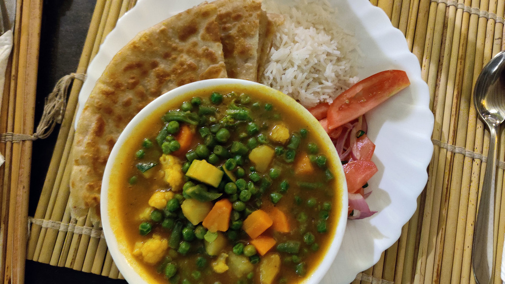 A bowl of curry and vegetables on a bamboo placemat in Kenya.